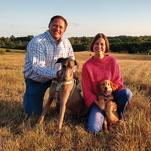 couple in a field with 2 dogs